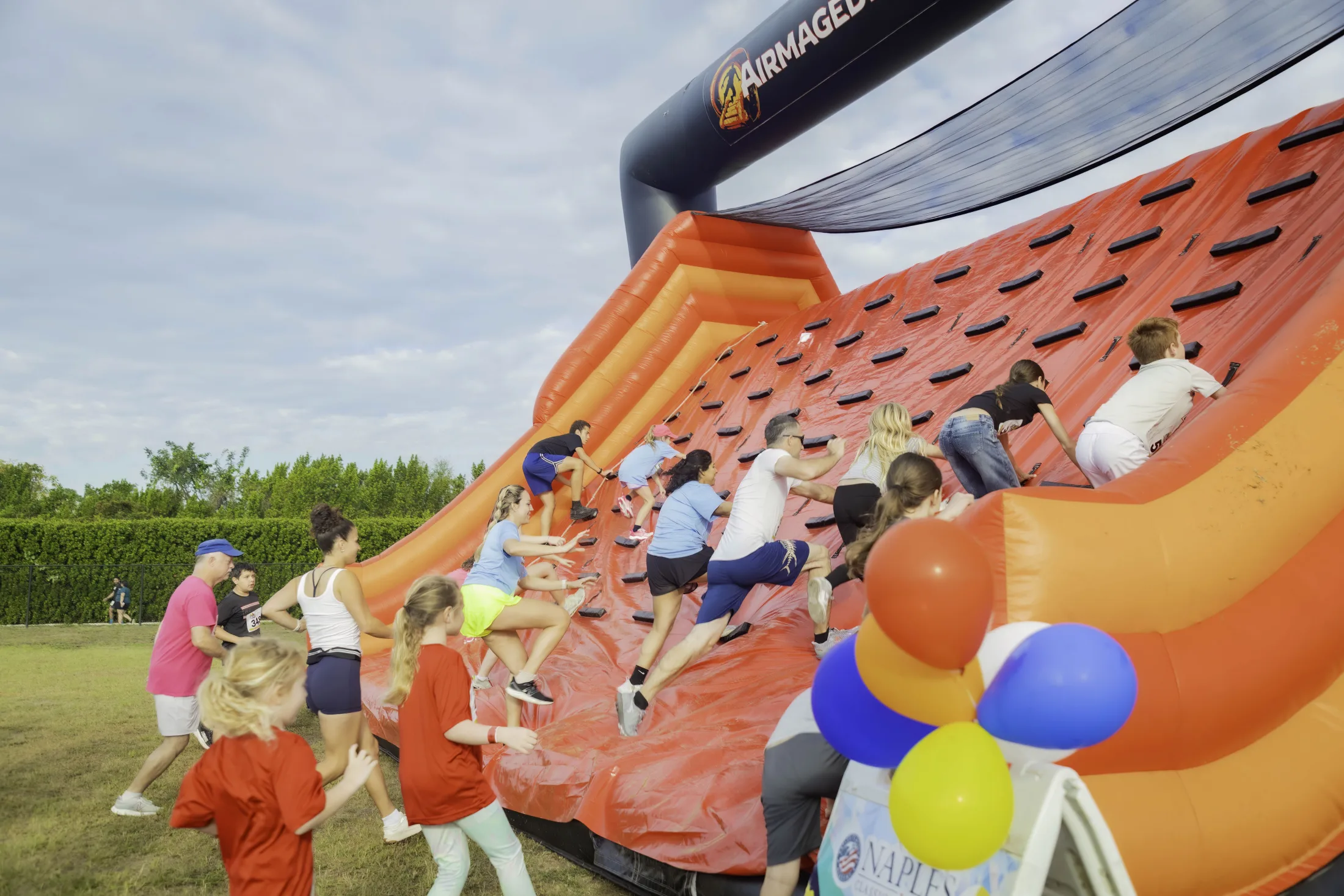 Participants climbing a giant orange and black obstacle at the Great Inflatable 5K